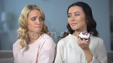 饥饿的女人在节食，看着她瘦瘦的朋友享受美味的蛋糕，羡慕